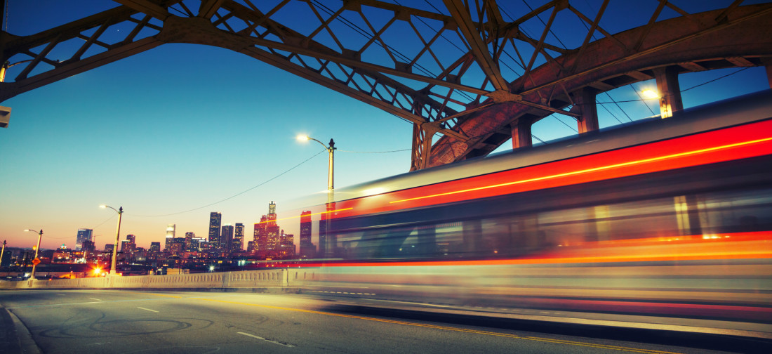 A bus moving in a blur heading into a city at dusk