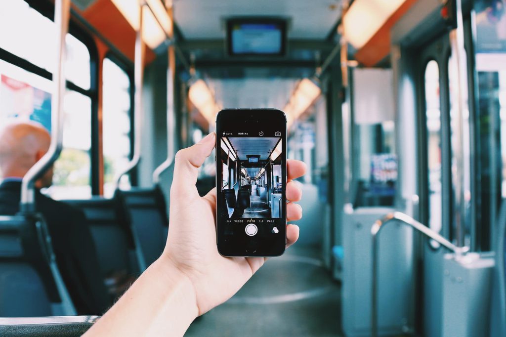 Hand holding a phone directly in front, travelling on public transport