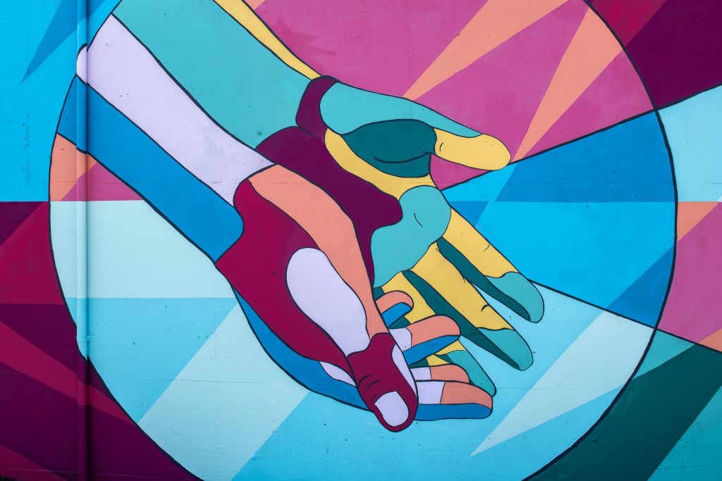 Brightly coloured street art style painting of hands reaching out