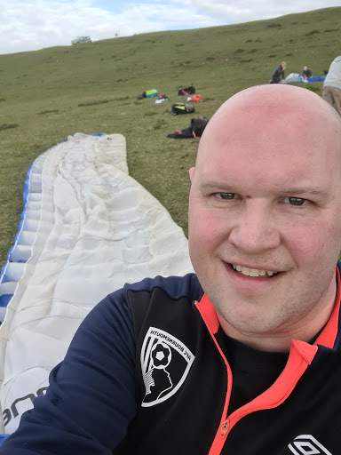 Andy standing on a hill side with a parachute on the ground