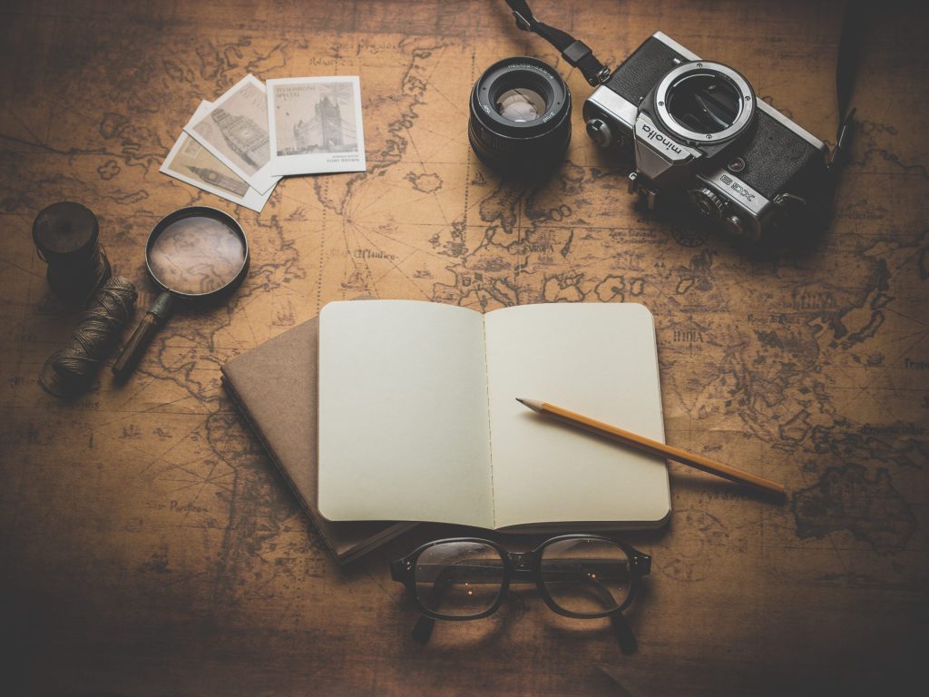 A map with a camera and open notebook laying on top.