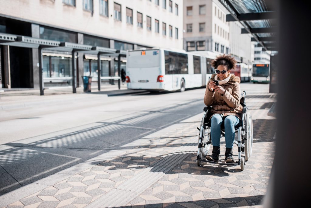 Person using their phone by a bus stop