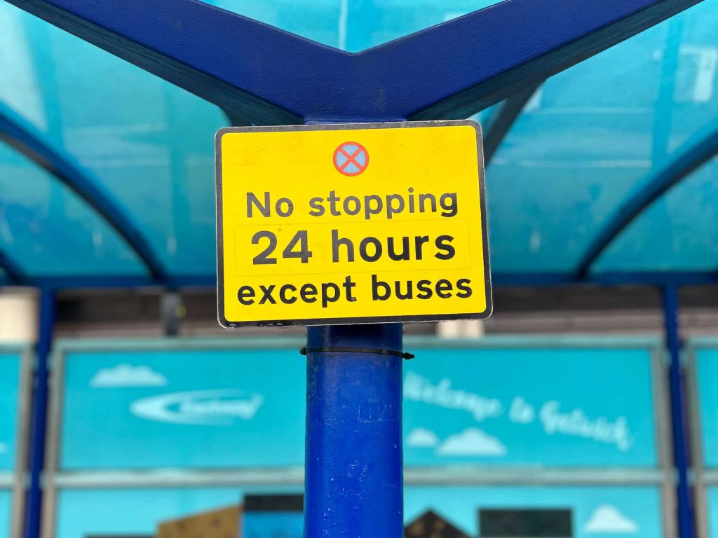 A road sign at a bus stop showing "No stopping 24 hours except buses".